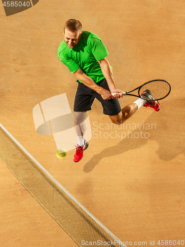 Image of The one jumping player, caucasian fit man, playing tennis on the earthen court