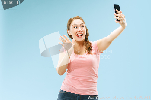 Image of Portrait of a happy smiling casual girl showing blank screen mobile phone isolated over blue background