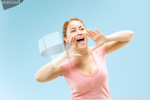 Image of Isolated on blue young casual woman shouting at studio