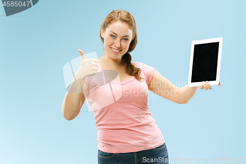 Image of Portrait of a confident casual girl showing blank screen of laptop isolated over blue background