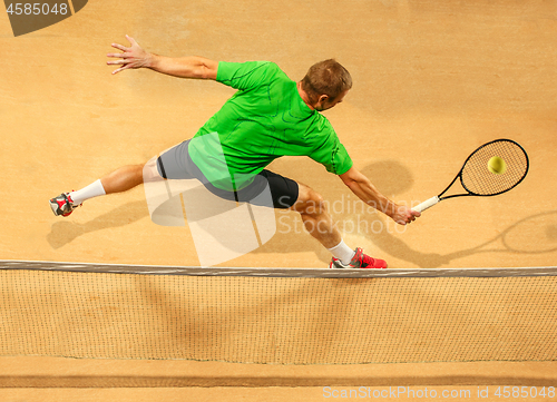 Image of The one jumping player, caucasian fit man, playing tennis on the earthen court