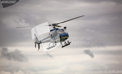 Image of Blue helicopter in flight over gray sky