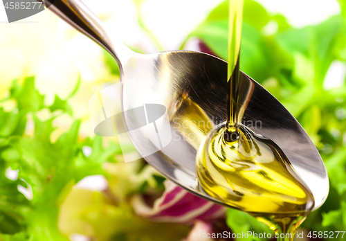 Image of Olive oil being poured into a spoon and salad