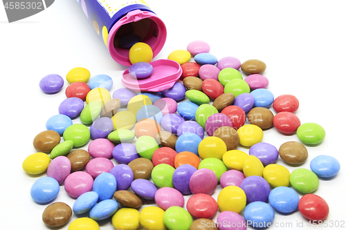 Image of Multicolored glazed chocolate candies out of the container 