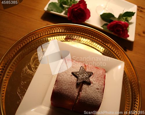 Image of Pastry to celebrate the New Year 2020 with red Roses in background