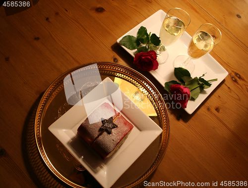 Image of Pastry, red Roses and two glasses of champagne for the new Year 2020