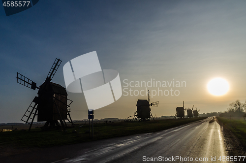 Image of Windmill silhouettes by roadside