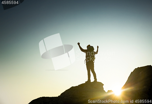 Image of Man with arms raised at sunset