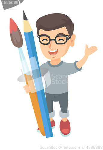 Image of Smiling boy holding big pencil and paintbrush.