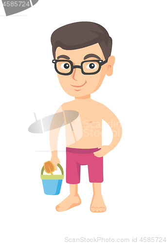 Image of Caucasian boy in shorts holding pail and shovel.