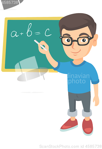 Image of Caucasian schoolboy writing on the blackboard.