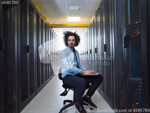 Image of engineer working on a laptop in server room