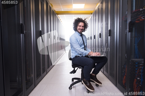 Image of engineer working on a laptop in server room