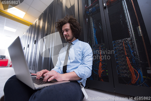 Image of engineer working on a laptop in server room