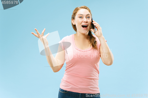 Image of Young beautiful woman using mobile phone studio on blue color background