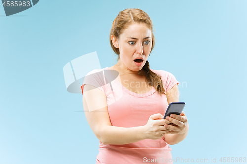 Image of Young beautiful woman using mobile phone studio on blue color background