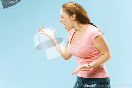 Image of Beautiful female half-length portrait isolated on blue studio backgroud. The young emotional surprised woman