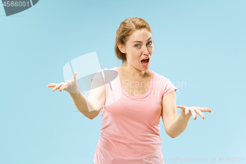 Image of Beautiful female half-length portrait isolated on blue studio backgroud. The young emotional surprised woman
