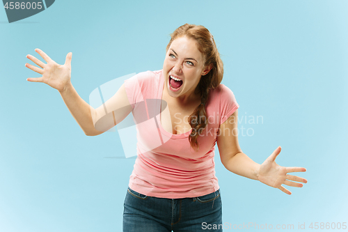 Image of The young emotional angry woman screaming on blue studio background