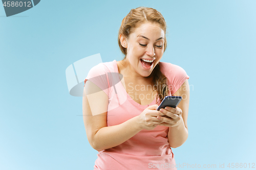 Image of Young beautiful woman using mobile phone studio on blue color background