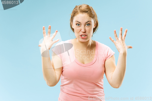 Image of Beautiful female half-length portrait isolated on blue studio backgroud. The young emotional surprised woman