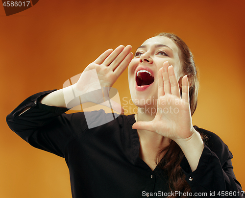 Image of Isolated on orange young casual woman shouting at studio