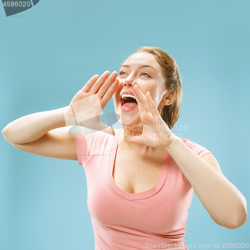 Image of Isolated on blue young casual woman shouting at studio