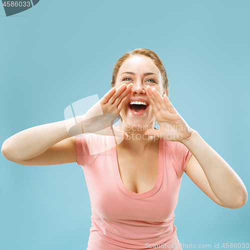 Image of Isolated on blue young casual woman shouting at studio