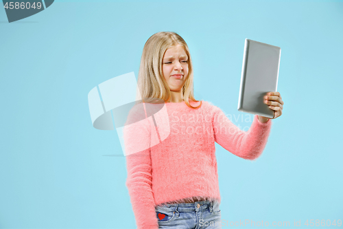 Image of Teen girl with laptop. Love to computer concept. Attractive female half-length front portrait, trendy blue studio backgroud.