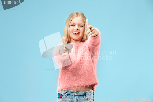 Image of The happy teen girl standing and smiling against blue background.