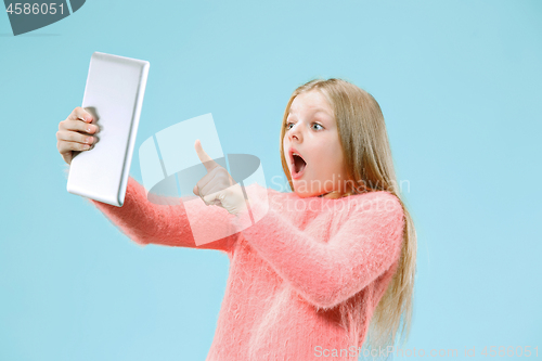 Image of Teen girl with laptop. Love to computer concept. Attractive female half-length front portrait, trendy blue studio backgroud.