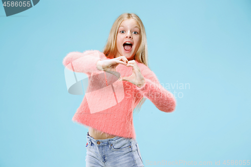 Image of Beautiful smiling teen girl makes the shape of a heart with her hands on the blue background.