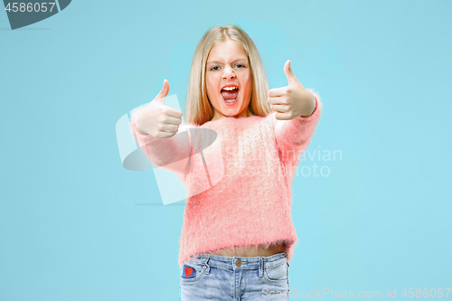 Image of The happy teen girl standing and smiling against blue background.