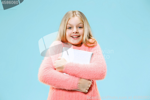 Image of Teen girl with laptop. Love to computer concept. Attractive female half-length front portrait, trendy blue studio backgroud.