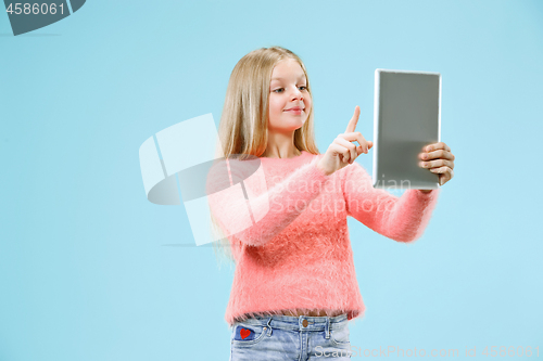 Image of Teen girl with laptop. Love to computer concept. Attractive female half-length front portrait, trendy blue studio backgroud.