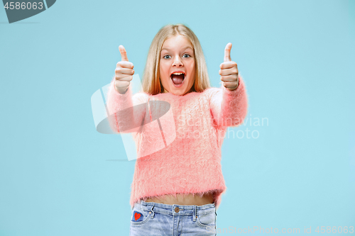 Image of The happy teen girl standing and smiling against blue background.