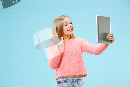 Image of Teen girl with laptop. Love to computer concept. Attractive female half-length front portrait, trendy blue studio backgroud.