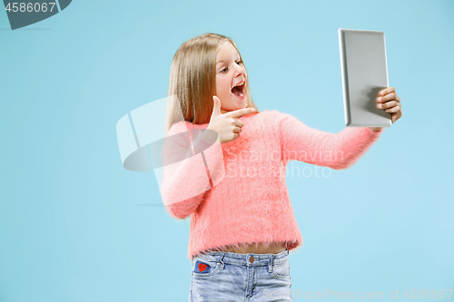 Image of Teen girl with laptop. Love to computer concept. Attractive female half-length front portrait, trendy blue studio backgroud.