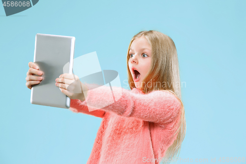 Image of Teen girl with laptop. Love to computer concept. Attractive female half-length front portrait, trendy blue studio backgroud.
