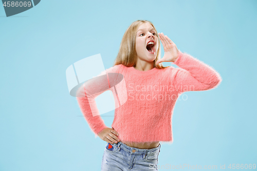 Image of Isolated on blue young casual teen girl shouting at studio