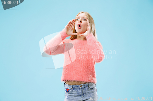 Image of Isolated on blue young casual teen girl shouting at studio