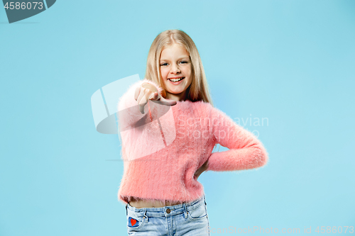 Image of The happy teen girl pointing to you, half length closeup portrait on blue background.