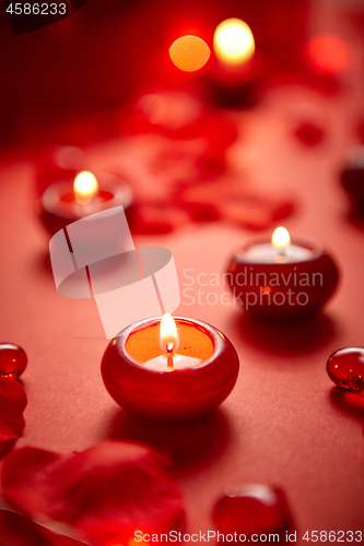 Image of Romantic dinner decoration. Red candles, flower petals, on the table