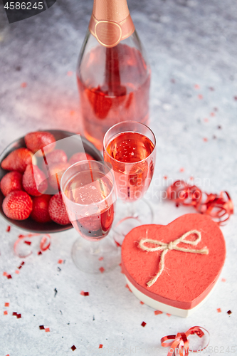 Image of Bottle of rose champagne, glasses with fresh strawberries and he