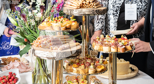 Image of Businesspeople at banquet lunch break at business conference meeting. Assortment of canapes and finger food on the table.