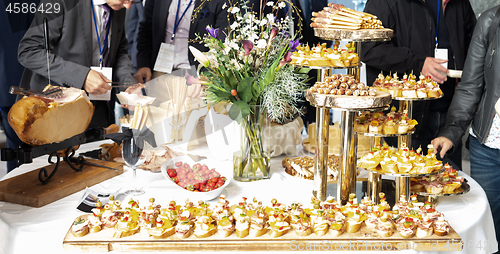 Image of Businesspeople at banquet lunch break at business conference meeting. Assortment of canapes and finger food on the table.