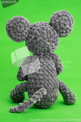 Image of Grey knitted mouse with a heart in hand on a green background, rear view