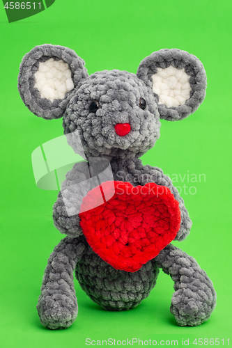 Image of Grey knitted mouse with a heart in hand on a green background