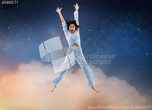 Image of happy woman in blue pajama jumping high