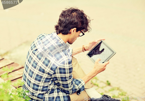 Image of man with tablet pc sitting on city street bench